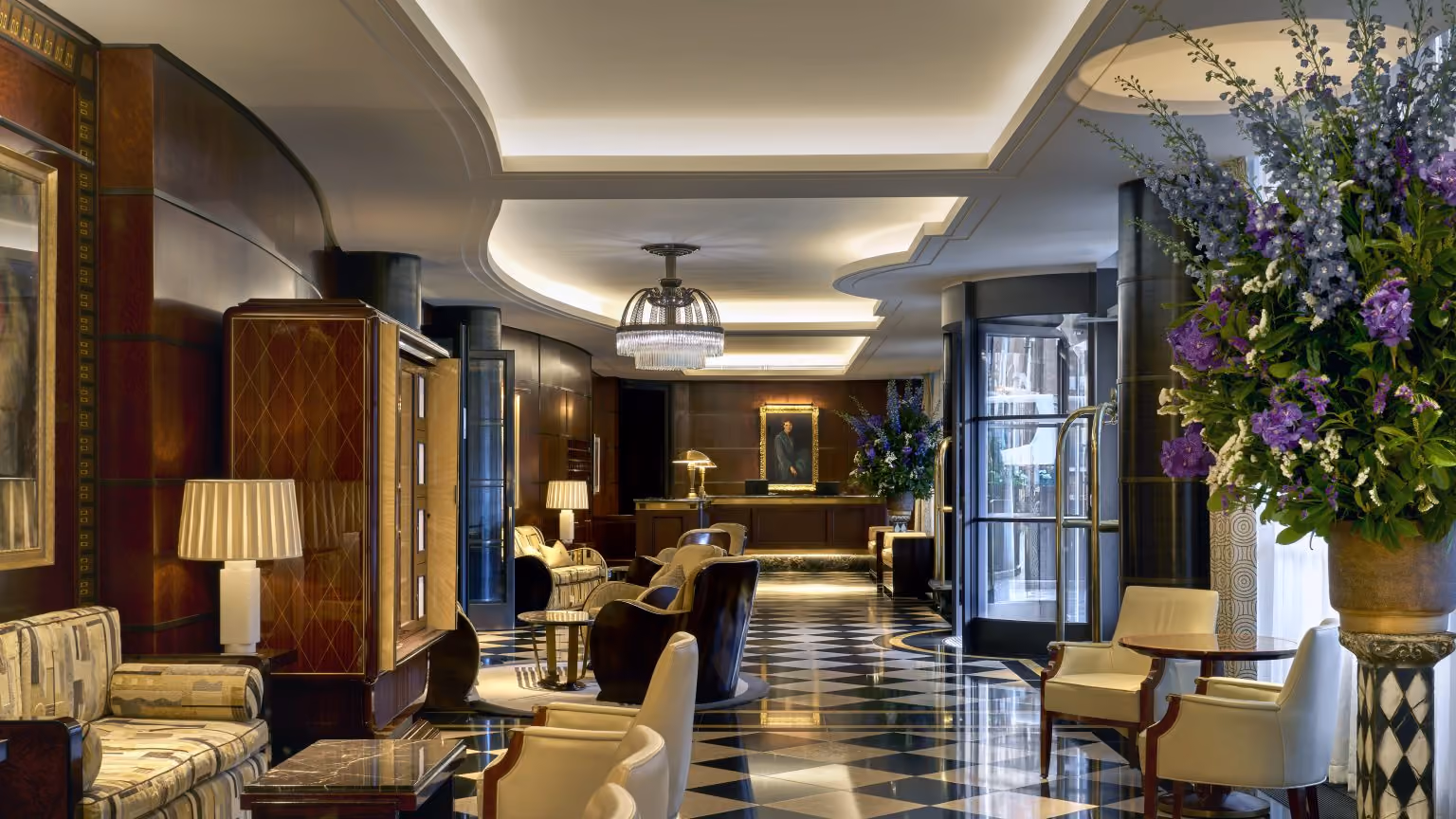 Lobby at The Beaumont in Mayfair, London, with Art Deco interiors, patterned flooring, lounge seating and floral arrangements.