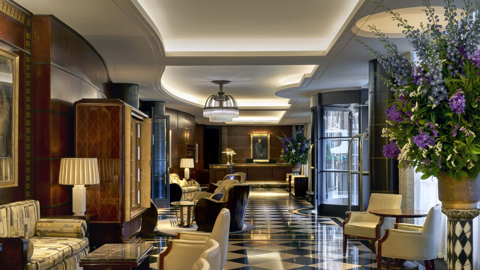 Lobby at The Beaumont in Mayfair, London, with Art Deco interiors, patterned flooring, lounge seating and floral arrangements.