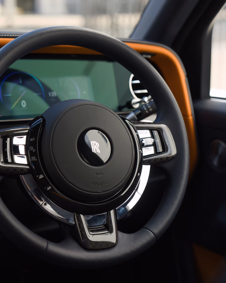 Close-up of the Rolls-Royce Cullinan steering wheel and digital cockpit, highlighting refined materials, polished detailing and the vehicle’s premium interior craftsmanship.