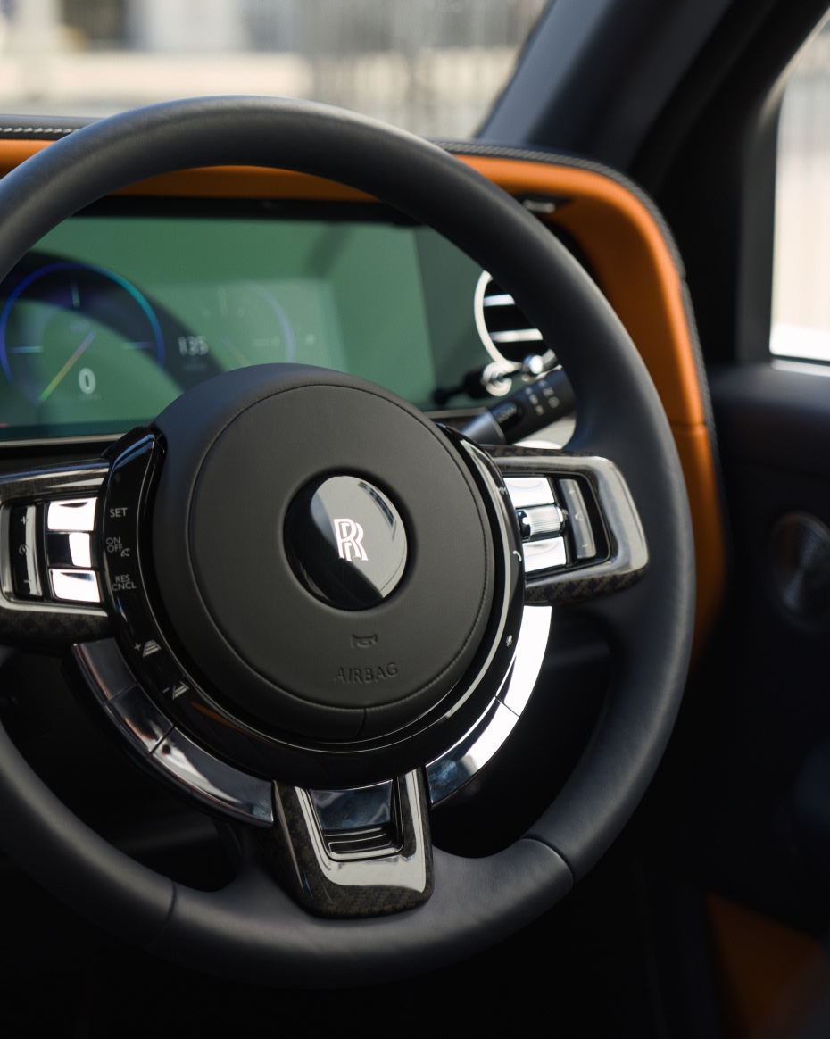 Close-up of the Rolls-Royce Cullinan steering wheel and digital cockpit, highlighting refined materials, polished detailing and the vehicle’s premium interior craftsmanship.