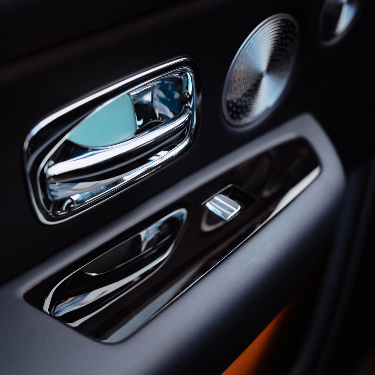 Close-up of the Rolls-Royce Cullinan rear door controls, polished metal trim and bespoke speaker detailing inside the luxury cabin.