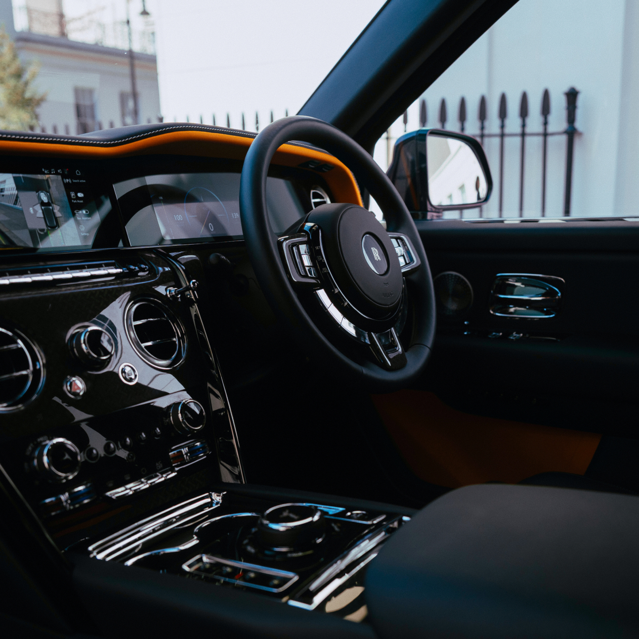 Interior view of the Rolls-Royce Cullinan driver cockpit, featuring the steering wheel, digital dashboard, polished controls and handcrafted cabin finishes.