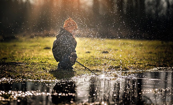 a kid splashing water with a stick