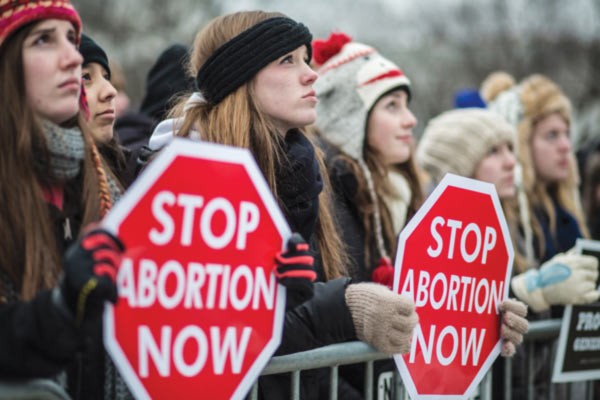 A line of women holding signs at a pro-life rally