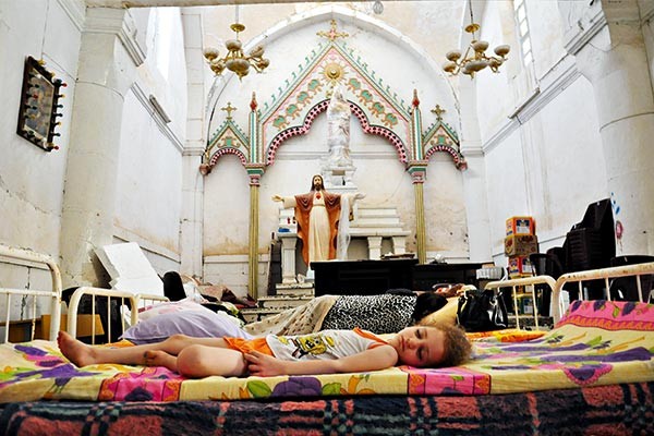 a young girl sleeping on a mattress in a church