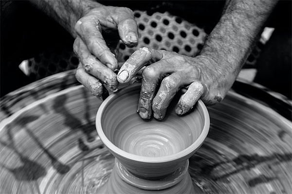 black and white photo of someones hands forming a bowl on a potters wheel
