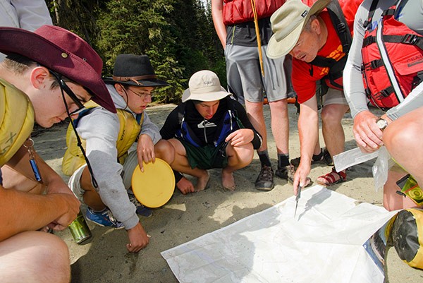 Boy Scouts and leader looking at a map on the ground