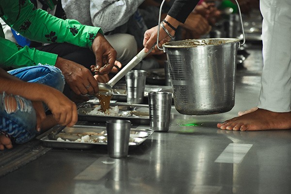 a man serving food in a community kitchen in India
