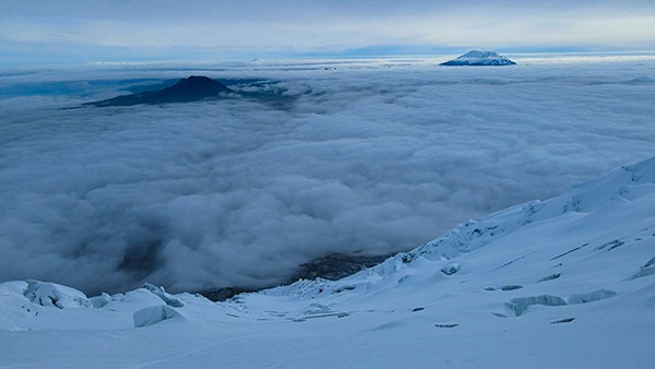 Snowcapped mountains peeping up from cloud layer