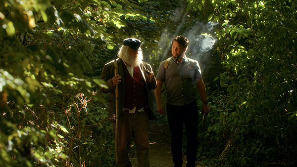two men walking on a path in the woods