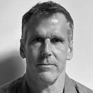 Black and white portrait of a middle-aged man with short hair and a neutral expression.