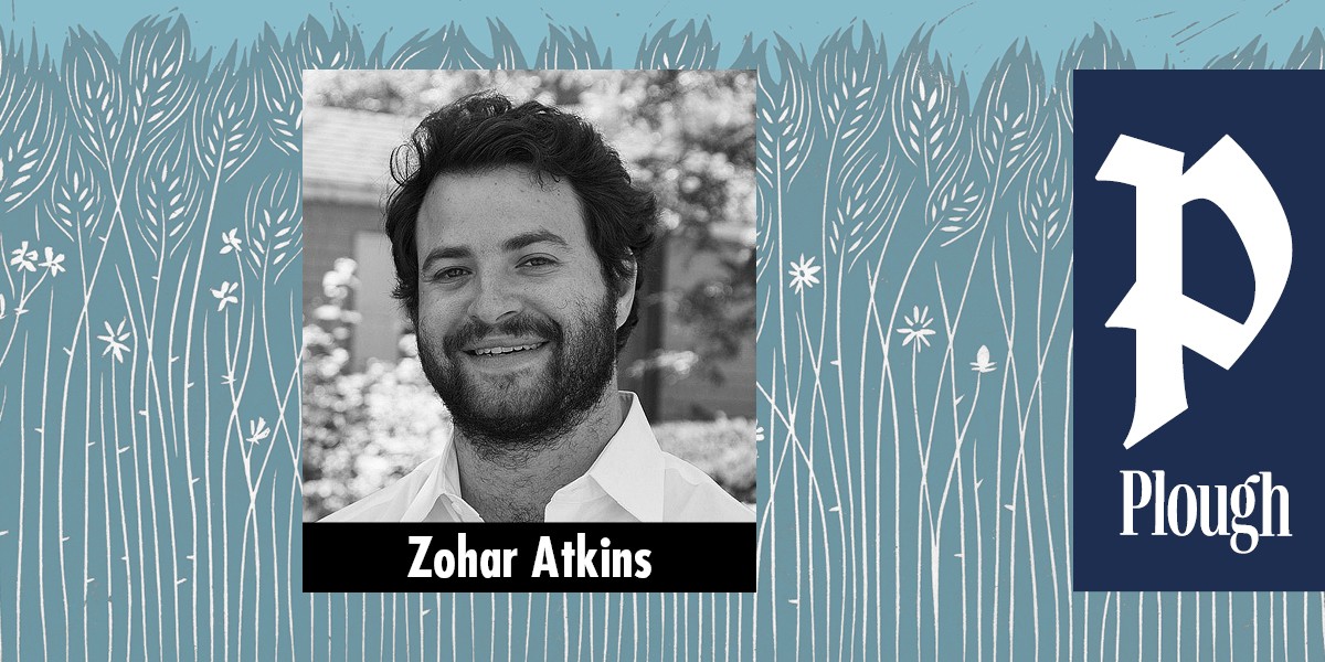 Black and white portrait of a smiling man with dark hair and beard named Zohar Atkins.