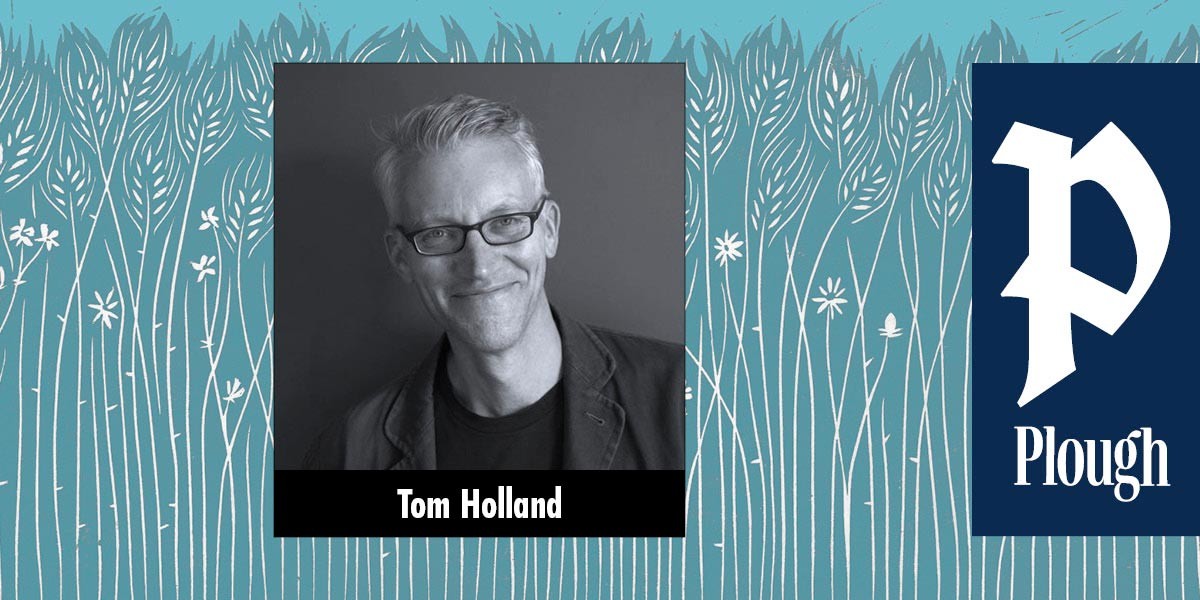 Black-and-white photo of a smiling man with glasses named Tom Holland on a blue wheat field background.