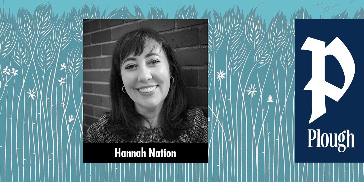 Black and white photo of a smiling woman with dark hair against a brick wall labeled Hannah Nation.