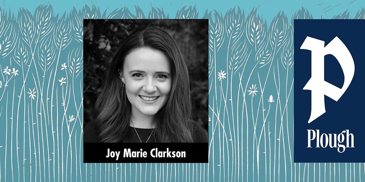 Black and white portrait of Joy Marie Clarkson smiling against a leafy background.