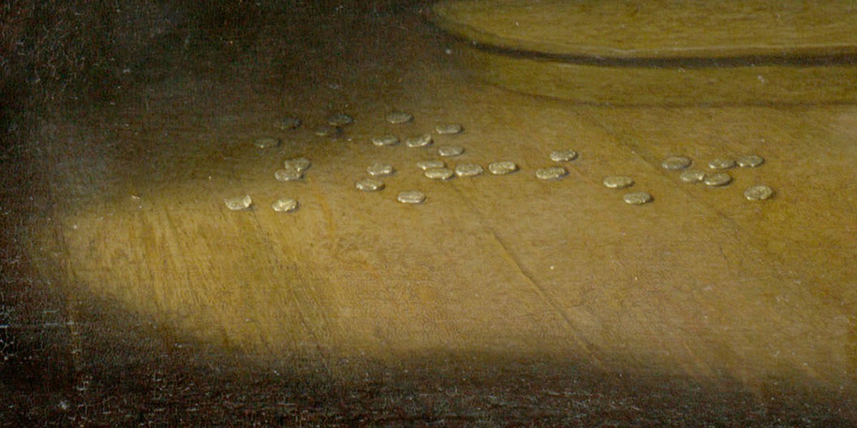 Close-up of a painting section with scattered gold coins on a wooden surface.