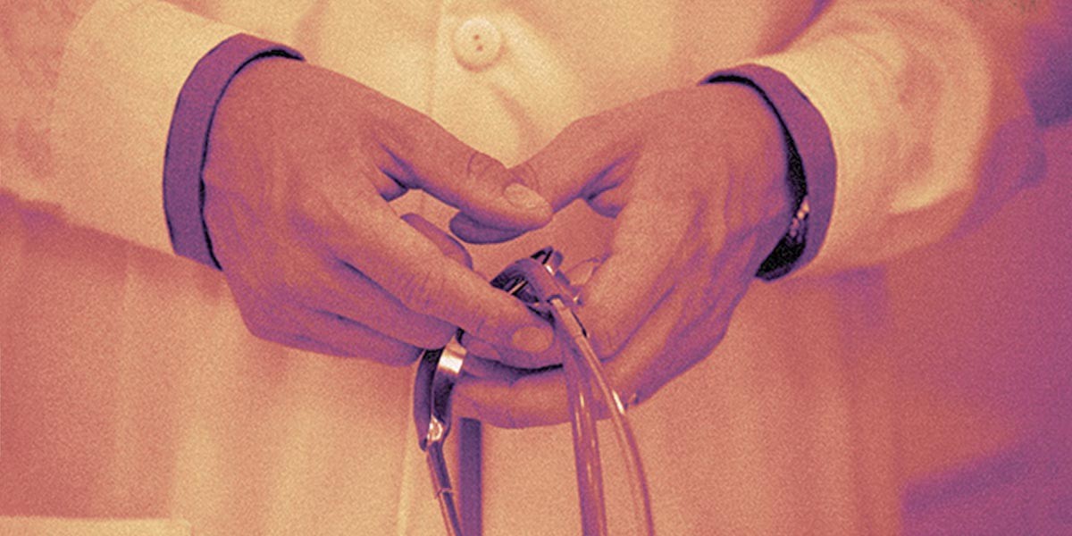 Hands of a person in a white coat holding a stethoscope.