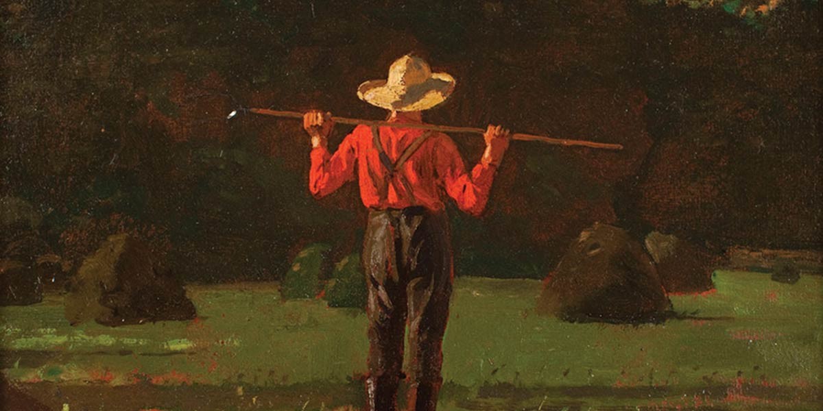 Back view of a farmer holding a long stick across his shoulders in a field with haystacks at dusk.