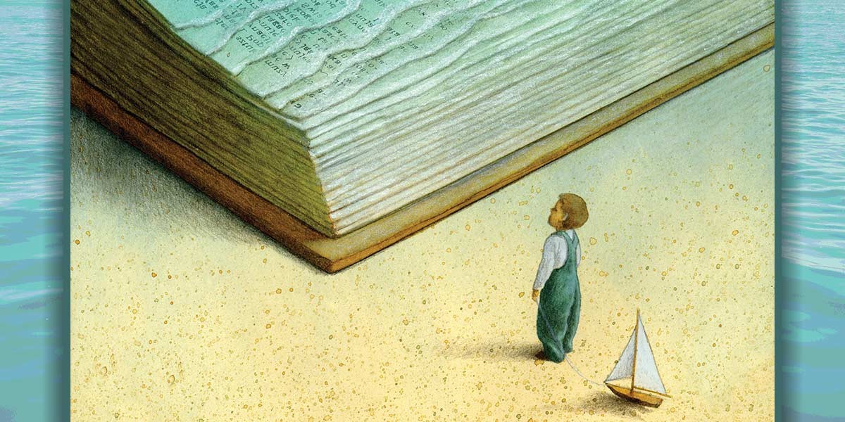 Small child in green overalls pulling a toy sailboat, looking up at a giant open book on sand.