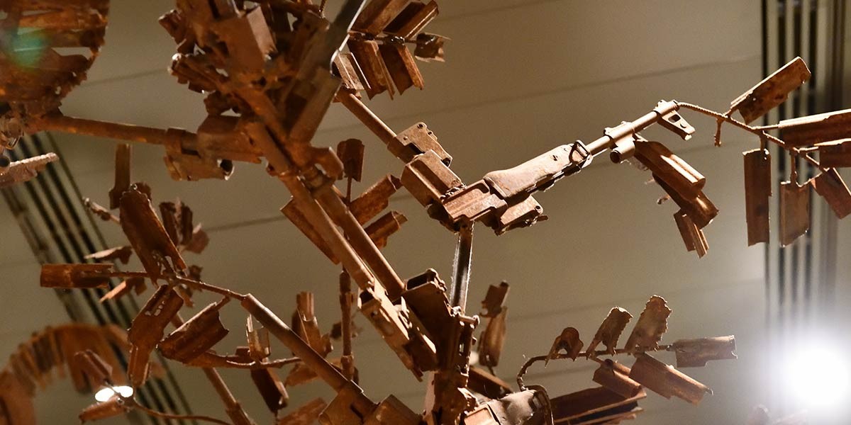 Rusty metal sculpture made from disassembled gun parts arranged on thin rods.