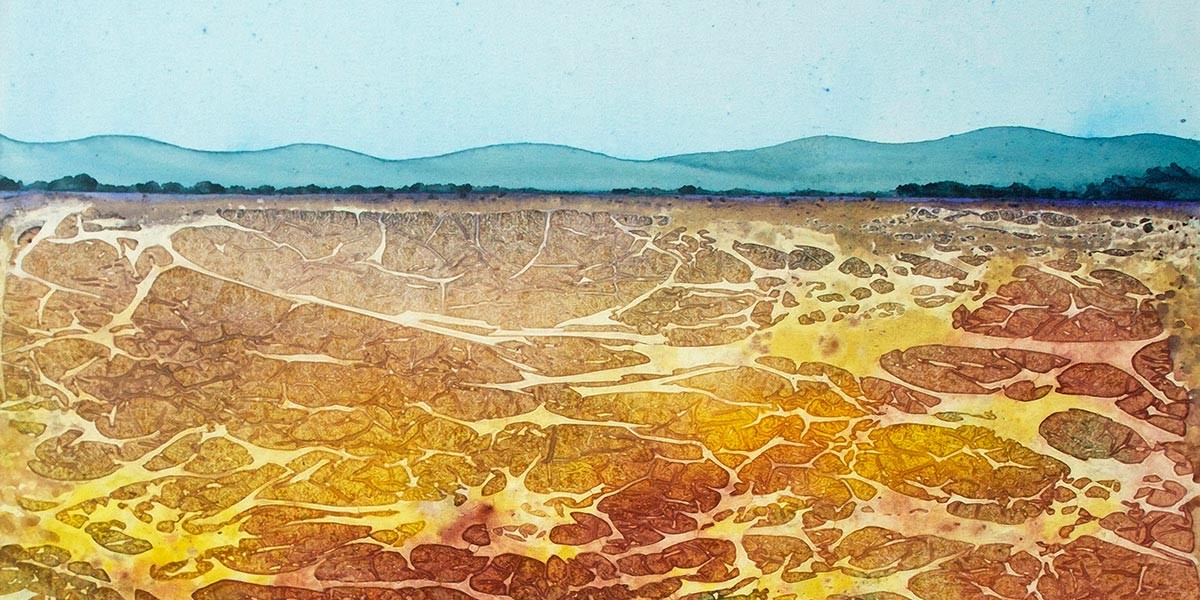 Abstract landscape with cracked earth in warm tones and distant blue hills under a pale sky.