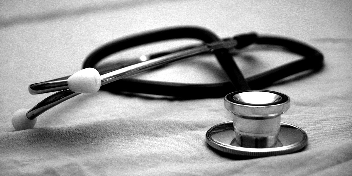 Close-up of a stethoscope resting on a fabric surface in black and white.