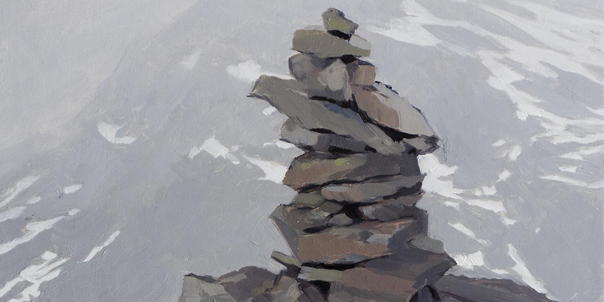 Stacked rocks forming a cairn or rock pile against a grey textured background.
