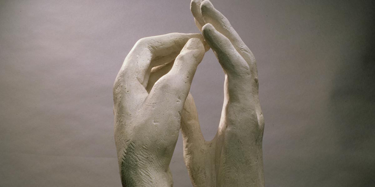 Close-up of a white sculpted pair of hands facing each other with fingers almost touching.