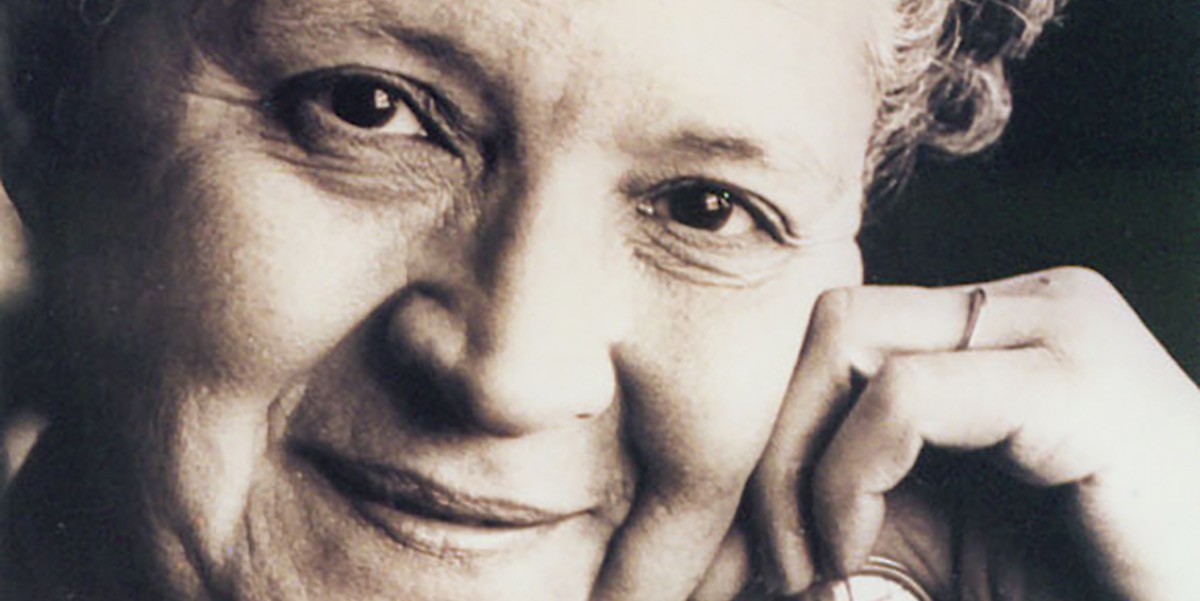 Close-up of an elderly woman resting her face on her hand, smiling gently.