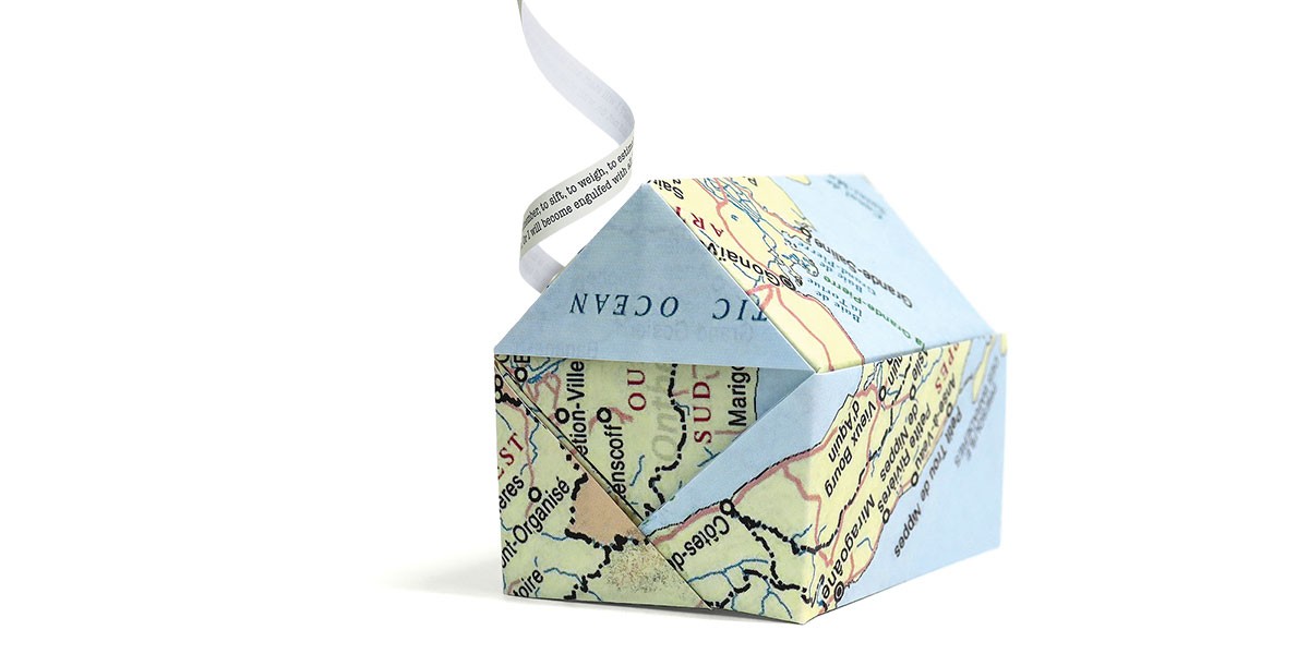 Origami house made from a map with a smoke-like paper strip curling above.