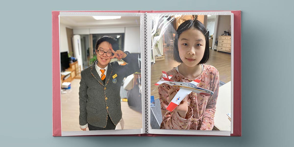 Photo album open to two pages showing a boy in school uniform and a girl holding a model airplane.