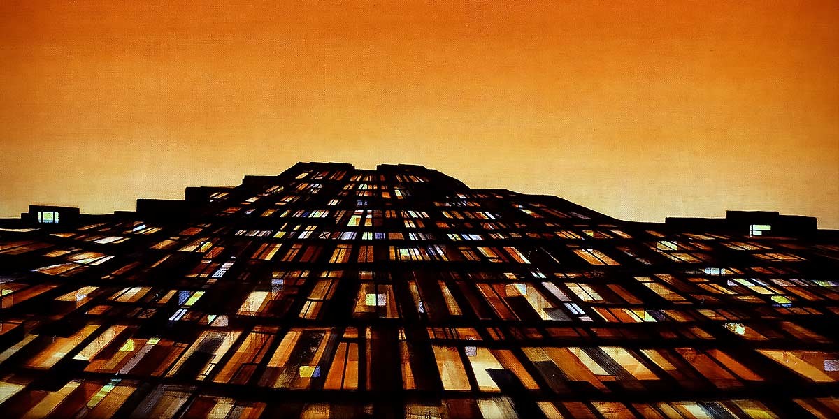 View looking up at a tall building with many lit windows against an orange sky at dusk.