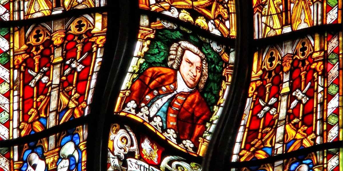 Stained glass window featuring a man in an 18th-century red coat with white wig and colorful ornamental designs.