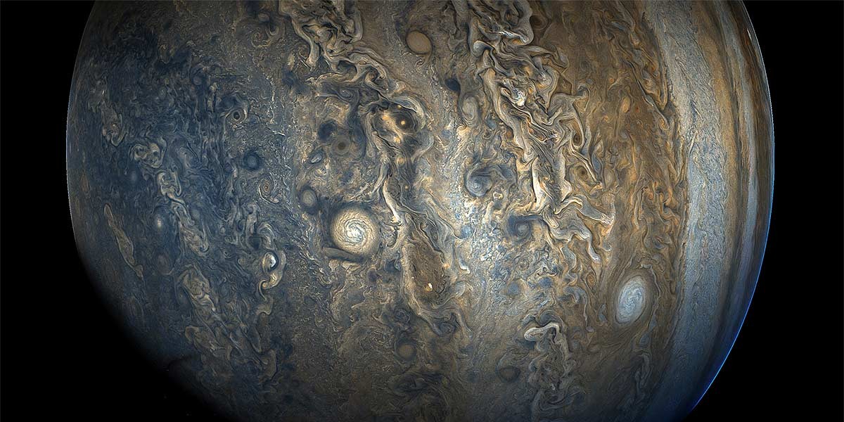 Swirling storm patterns and cloud formations on Jupiter's surface against black space.