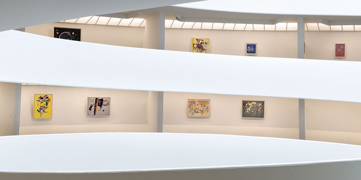 Interior view of a modern circular art gallery with abstract paintings on the walls.