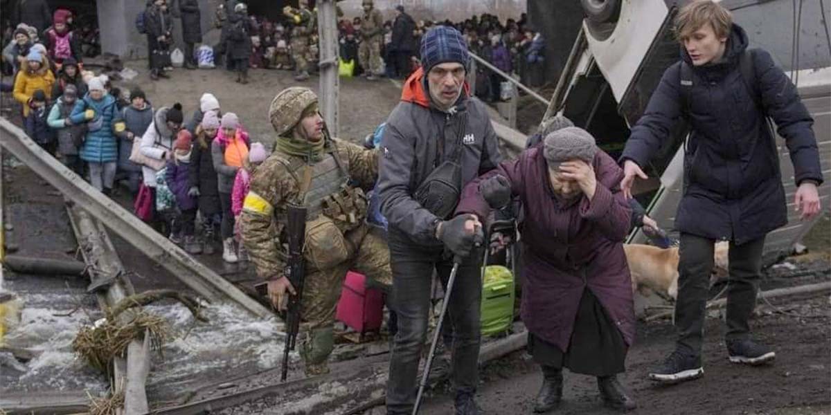 People, including soldier, man with cane, and woman, evacuate across damaged bridge with crowd in background.