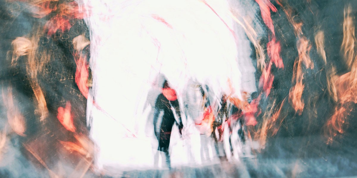 Abstract blurry image of people walking with swirling orange and white light streaks.