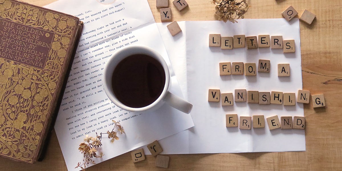 Wooden tiles spell 'Letters From A Vanishing Friend' next to a cup of tea, dried flowers, and a book.