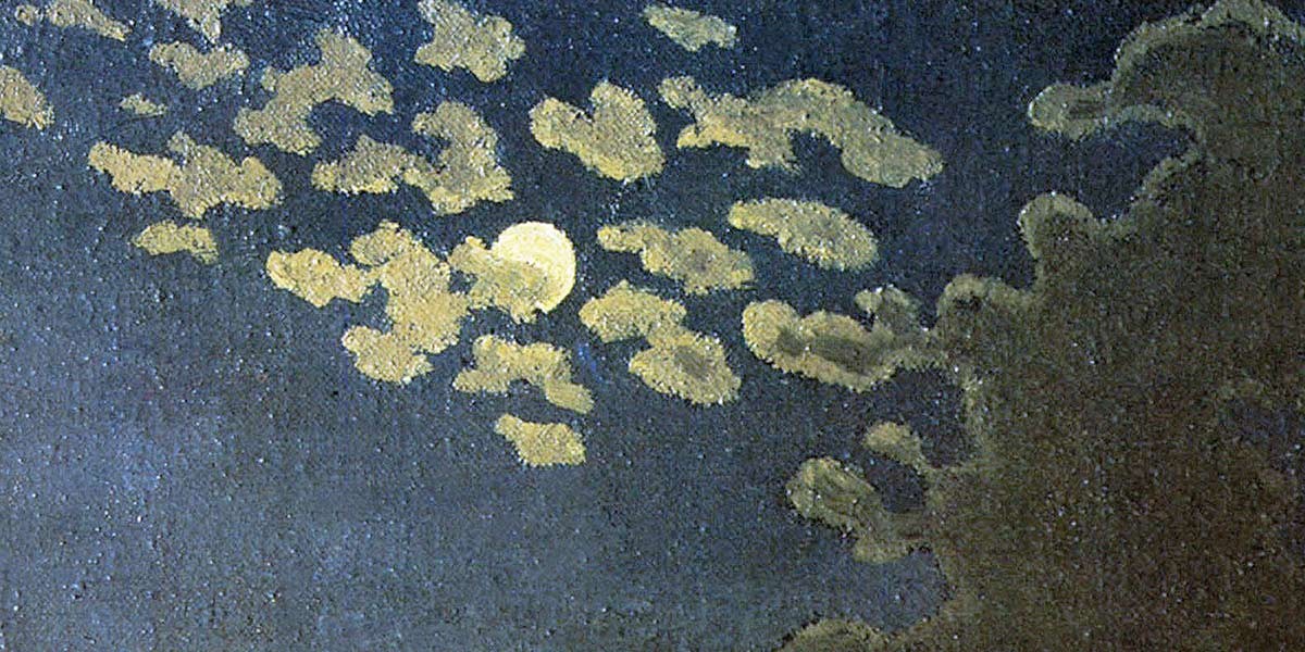 Moon partially obscured by scattered clouds in a dark night sky above silhouetted treetops.