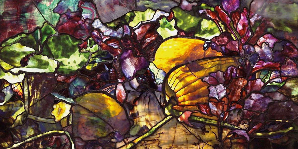 Colorful stained glass artwork featuring abstract leaves and flowers in green, yellow, purple, and red hues.