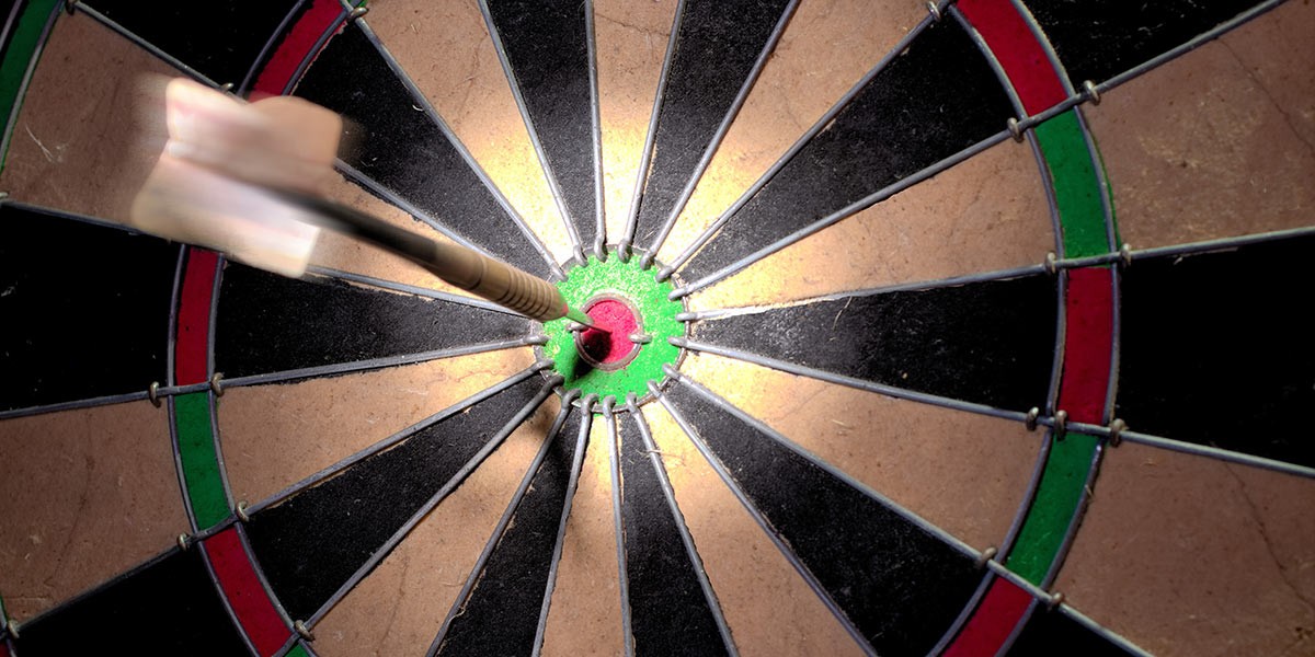 Close-up of a dart hitting the bullseye on a dartboard with motion blur on the dart's flight.