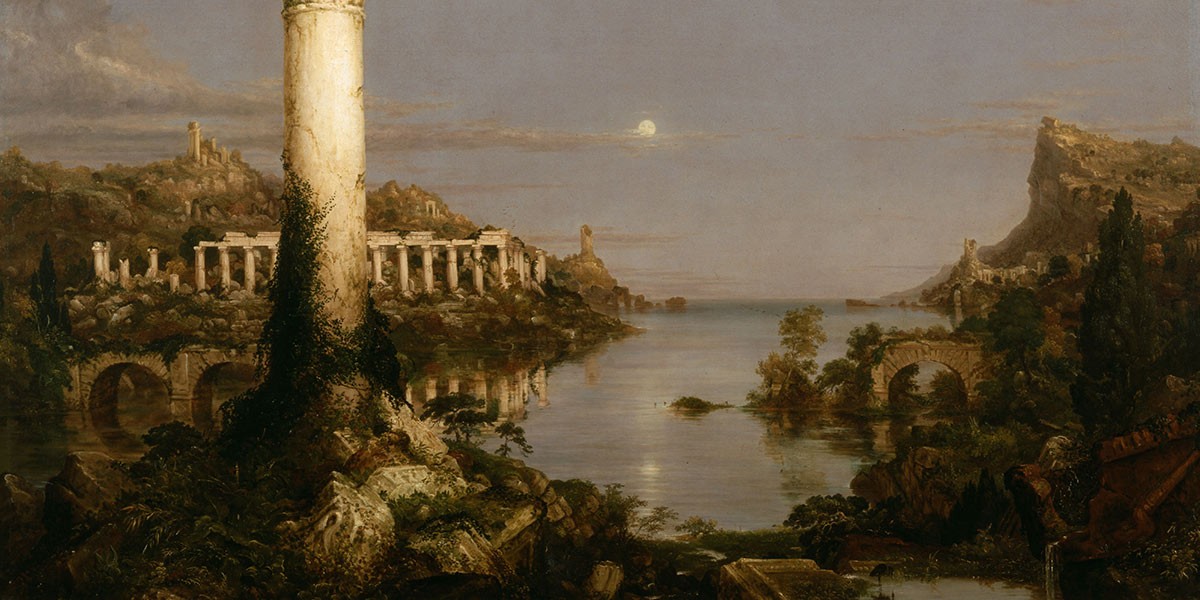 Ruins of ancient columns and arches around a calm body of water with hills at dusk under a cloudy sky.