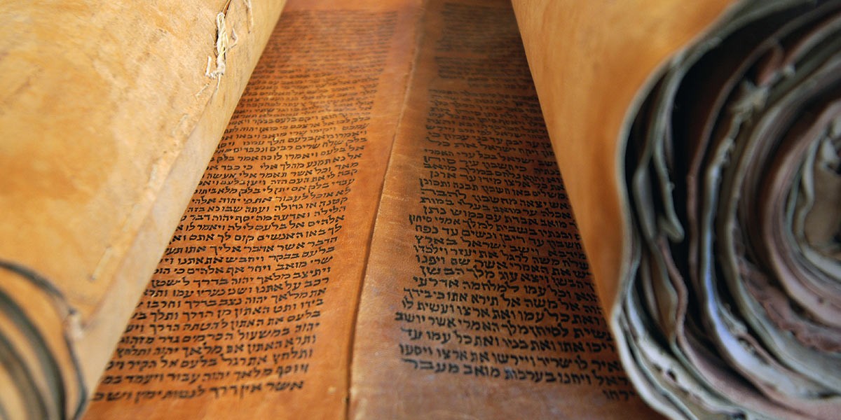 Close-up of an ancient rolled parchment scroll with Hebrew script text.
