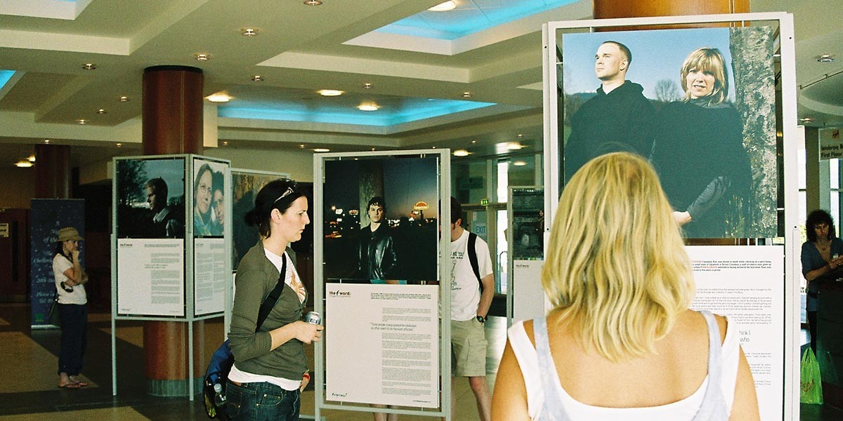People viewing portrait photo displays with text in a well-lit indoor public space.