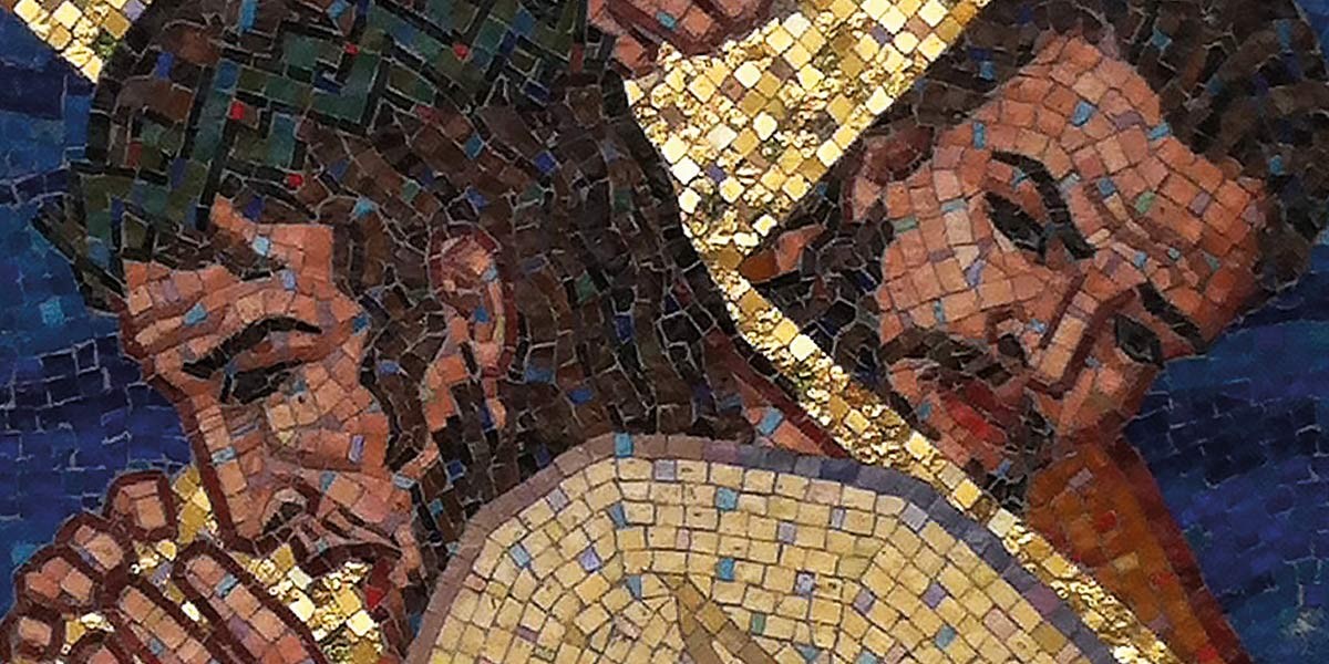 Mosaic artwork depicting two men in close embrace, rendered in brown, gold, and blue tiles.