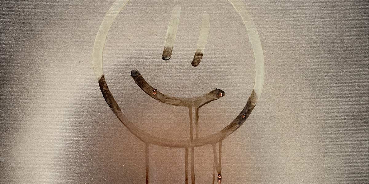 Smiley face drawn on a fogged glass surface with water droplets dripping down.