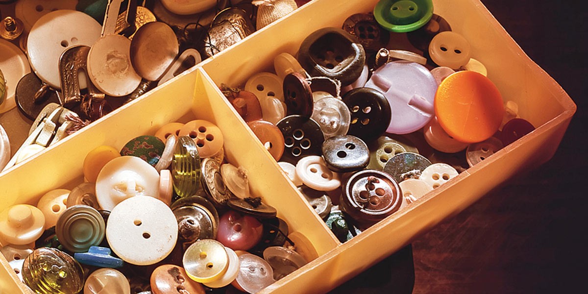 Close-up of a box filled with assorted buttons of various colors, sizes, and shapes.