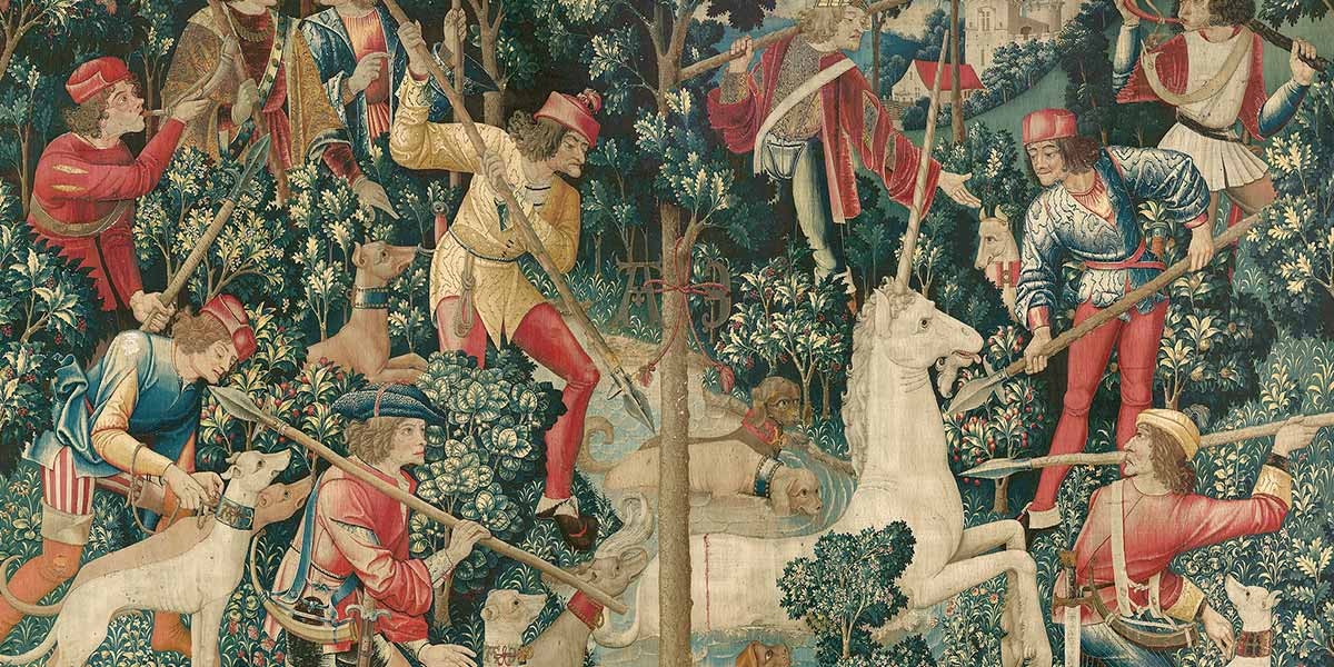 Medieval tapestry depicting hunters with spears and dogs surrounding a white unicorn in a forest.