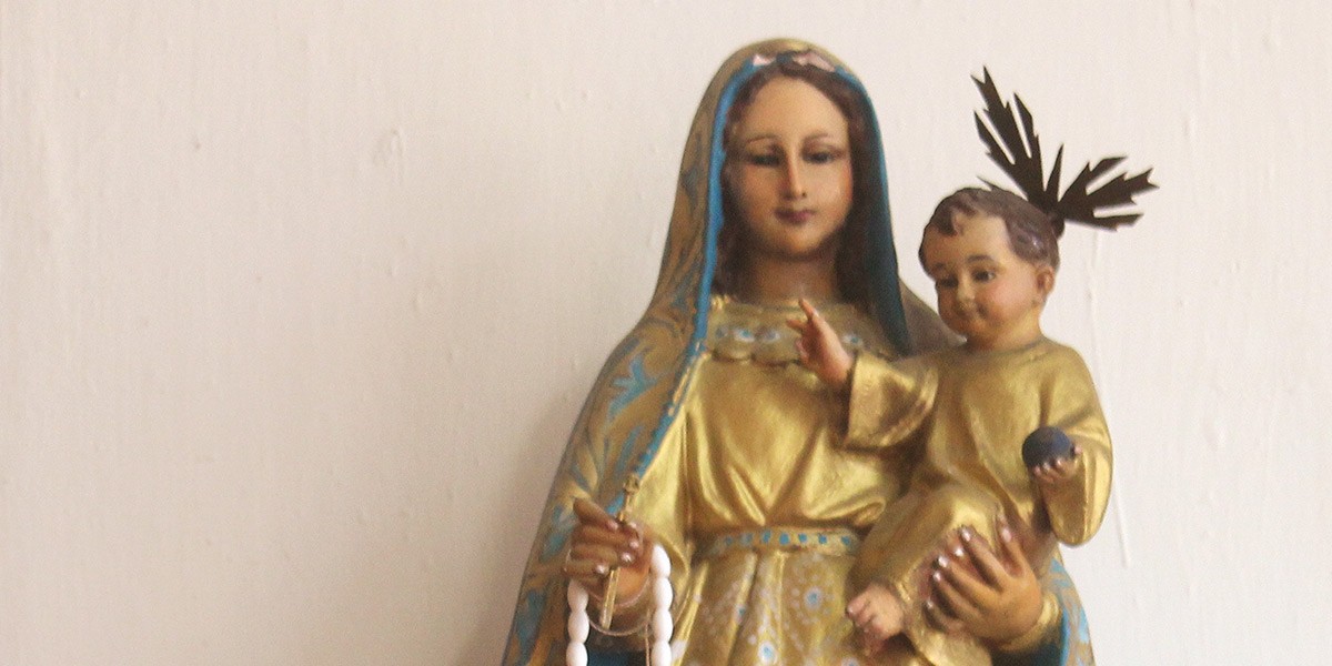Statue of Virgin Mary holding baby Jesus, both dressed in gold with blue accents.