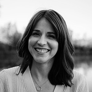 Black and white portrait of a smiling woman with shoulder-length hair wearing a necklace.